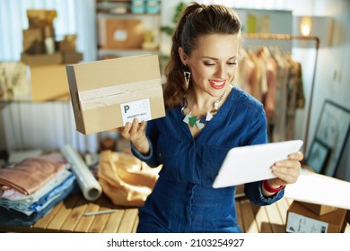 Happy Elegant 40 Years Old Small Business Owner Woman With Parcel Having Webcam Meeting On A Tablet PC In The Office.