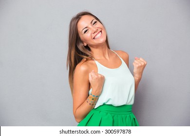 Happy elegant girl celebrating her success over gray background
