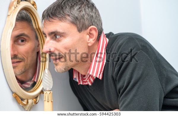Happy elegant man in the forties reflecting in\
the mirror.