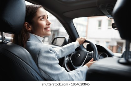 Happy elegant woman driver looking at person sitting in her car, pick up passenger. Businesswoman drop friend to meeting. Female executive talking to someone through car window.