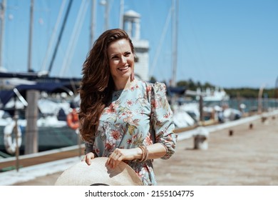 happy elegant woman in floral dress with hat on the pier.