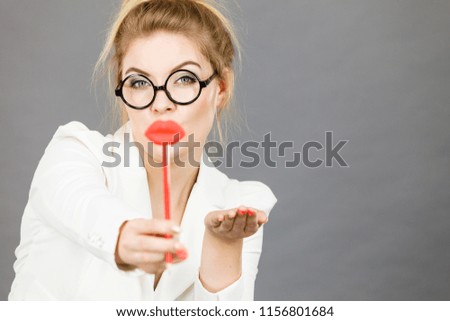 Happy elegant woman holding carnival accessoies on stick having fun at work wearing white office jacket