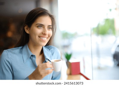 Happy elegant woman smiling drinking coffee in a bar interior looking through a window - Powered by Shutterstock