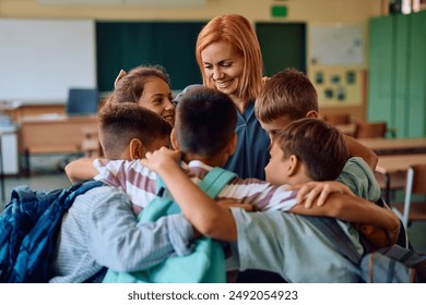 Happy elementary school teacher and her students embracing while greeting on first day of school.  - Powered by Shutterstock