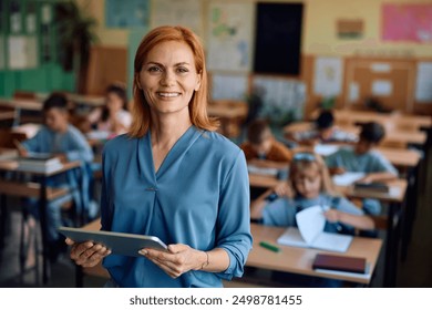 Happy elementary school teacher using touchpad in the classroom and looking at camera. Her students are learning in the background. - Powered by Shutterstock