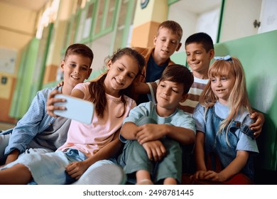 Happy elementary students taking selfie with cell phone at school.  - Powered by Shutterstock