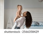 Happy embraces. Affectionate millennial mom lift little preschooler daughter kid up in air for loving hug bonding single parent and child cuddling laughing together at warm cozy bedroom in family home