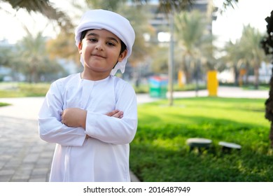 Happy Emirati child wearing white Kandura  clothes. Closed arms portrait of Arabic Middle Eastern boy wearing dish dash 