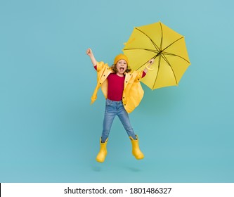 Happy Emotional Child Laughing And Jumping. Kid With Yellow Umbrella On Colored Teal Background.