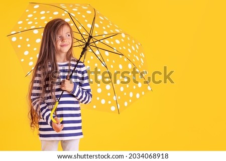 Happy emotional girl laughing with umbrella on colored yellow background. Autumn, spring season.