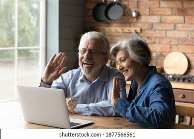 Happy Emotional Middle Aged Old Family Couple Making Hello Gesture, Waving Hands At Computer Web Camera, Starting Video Call Conversation With Friends Or Grown Children At Home, Distant Communication.