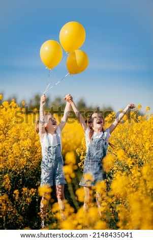 Happy emotions of children who are playing with balls on a yellow field of flowering rapeseed.