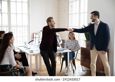 Happy Employee Congratulating Colleague On Work Achievement Or Promotion At Corporate Meeting. Male Coworkers Giving Fist Bumps As Gesture Of Unity, Friendship, Team Success. Teamwork, Praise Concept