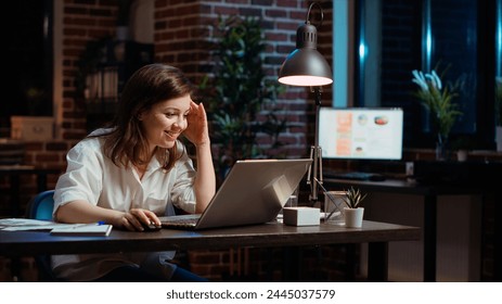 Happy employee reading email on laptop received from customer, excited after managing to secure lucrative deal for company. Businesswoman celebrating finalizing agreement with client, camera B