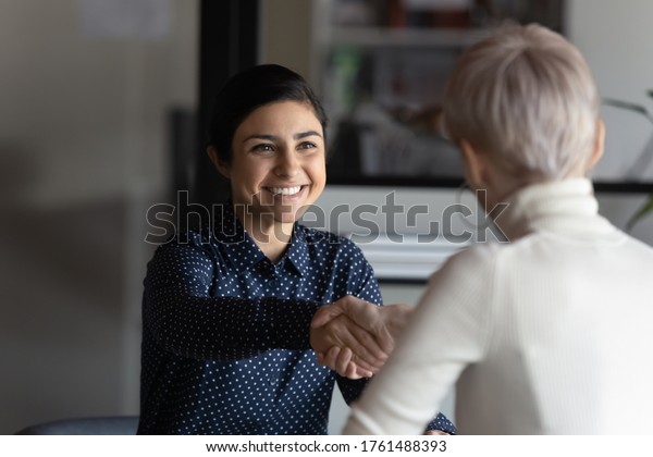 Happy employer HR manager shaking hands with\
indian job seeker welcoming vacancy applicant. Successful manager\
making deal with partner, good positive first impression, start\
business meeting concept