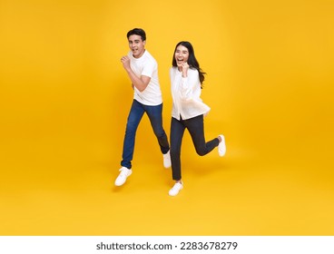 Happy energetic Asian couple running to shopping black friday low prices summer sale isolated on yellow studio background. - Powered by Shutterstock