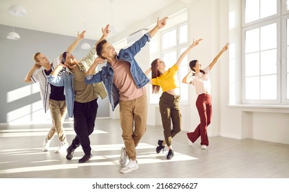 Happy energetic young hip-hop dancers dance together in bright spacious dance studio. Active young women and men in modern casual clothes pursue their hobbies and learn new dance movements together. - Powered by Shutterstock