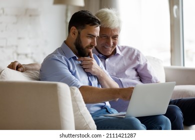 Happy engaged grownup son teaching senior 70s dad to use internet application on laptop, sharing computer, spending leisure time with father, watching movie, using digital service for entertainment - Powered by Shutterstock