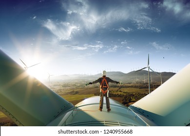 Happy engineer feel success after good work. He standing a top of windmill and looking beautiful sunset landscape - Shutterstock ID 1240955668