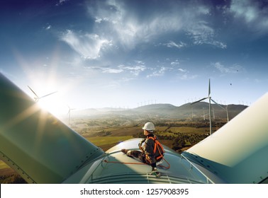 Happy engineer feel success after good work. He standing a top of windmill and looking beautiful sunset landscape - Shutterstock ID 1257908395