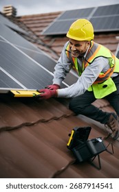 Happy engineer using level while mounting solar panel system on the rooftop.