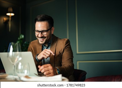 Happy entrepreneur looking at laptop in restaurant, portrait. - Powered by Shutterstock