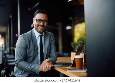 Happy entrepreneur using computer during his coffee break in a cafe and looking at camera. Copy space.  - Powered by Shutterstock