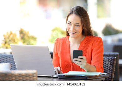 Happy Entrepreneur Using Multiple Electronic Devices Sitting In A Coffee Shop Terrace