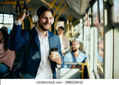Happy entrepreneur wearing headphones and listening music while traveling to work by bus. 