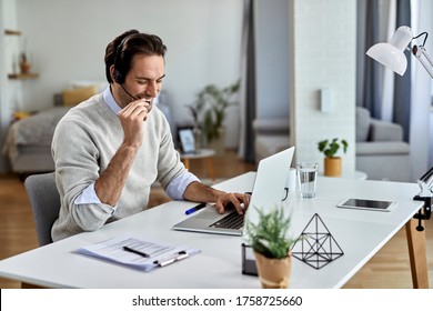 Happy Entrepreneur Wearing Headset And Talking To Someone While Working On Laptop At Home