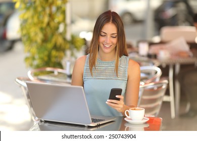 Happy entrepreneur working with a phone and laptop in a coffee shop in the street - Powered by Shutterstock