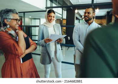 Happy entrepreneurs smiling cheerfully during a business meeting in a modern office. Group of successful business professionals working as a team in a multicultural workplace.