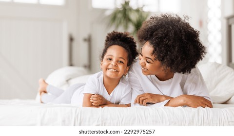 Happy ethnic family. African american mother and daughter play and laugh in bed an home - Powered by Shutterstock