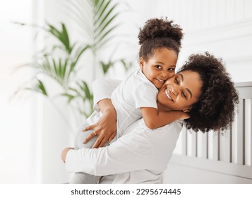 Happy ethnic family. African american mother and daughter play and laugh in bed an home