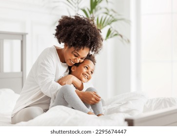 Happy ethnic family. African american mother and daughter play and laugh in bed an home - Powered by Shutterstock