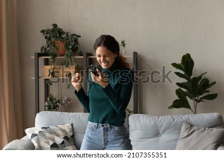 Happy euphoric millennial generation hispanic latin woman looking at mobile phone screen, feeling excited reading message with amazing win news, jumping dancing alone in living room, internet success. Stock photo © 