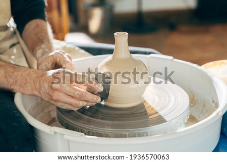 Happy european artisan man creating ceramic piece on spinning pottery wheel