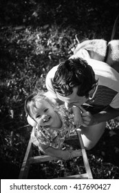 Happy European Child Climbing The Vertical Ladder. Father Helps And Protects His Adorable Little Kid. Playground Outdoors. Walk In The Fresh Air. Daughter, Baby, Girl. Photo In Black And White