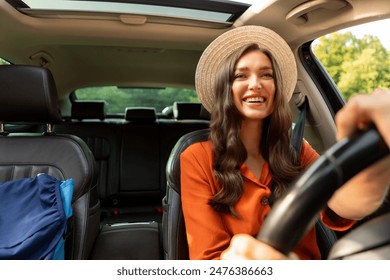 Happy European woman driving car alone, going on trip with backpack on passenger seat nearby. Journey and transportation concept - Powered by Shutterstock