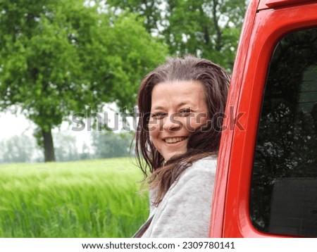happy european woman leaning against a red metal