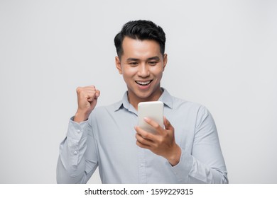 Happy Excited Asian Man Looking At His Smartphone And Raising His Arm Up To Celebrate Success 