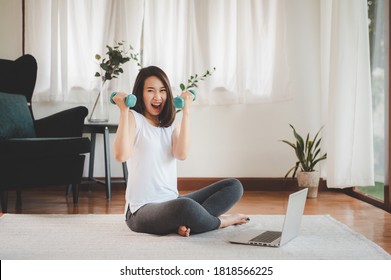 Happy And Excited Asian Woman Holding Dumbbells In Both Hand Feeling Ready To Exercises Workout At Home With Laptop 