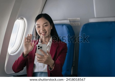 happy excited asian women waved to greet friends using a smartphone in airplane.