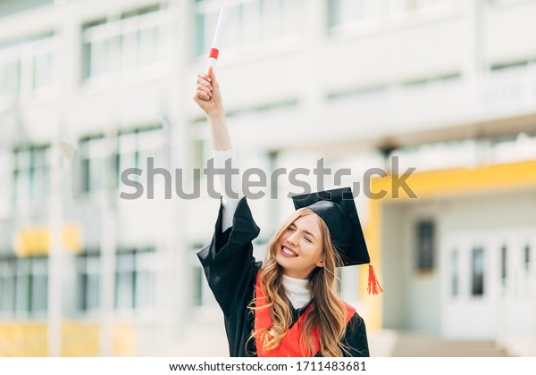 Happy excited beautiful graduate student with a\
University degree, shows a victory gesture and is happy. Concept of\
the graduation ceremony