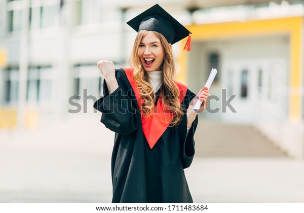 Happy excited beautiful graduate student with a\
University degree, shows a victory gesture and is happy. Concept of\
the graduation ceremony