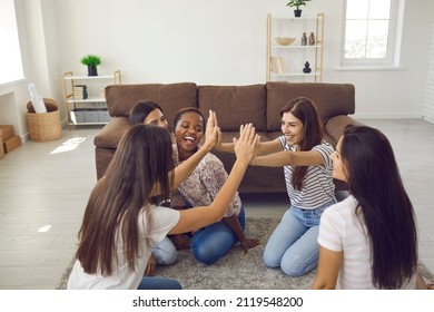 Happy Excited Best Friends High Fiving Each Other Sitting On Floor At Home. Diverse Group Of Positive Cheerful Confident Young Women Having Fun Together At Casual Gathering In Friend's Apartment