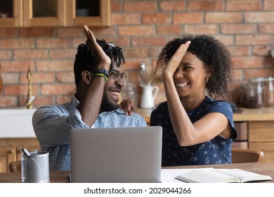 Happy excited Black mixed race couple celebrating financial success at laptop, getting income, loan, mortgage bank approval, planning good family budget. Young husband and wife giving high five - Shutterstock ID 2029044266