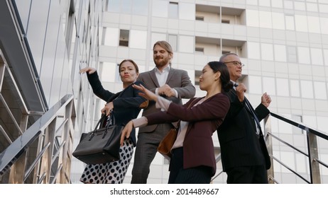 Happy Excited Business People Celebrating Success Together Dancing Outside Office Building. Cheerful Colleagues In Formal Wear Having Fun And Dance Outdoors Business Center