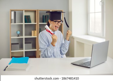 Happy Excited College Or University Student Sitting At Desk With Laptop, Holding Diploma And Celebrating Success As She Graduated With Excellent Grades, Managed To Get Good Job Or Win Research Grant