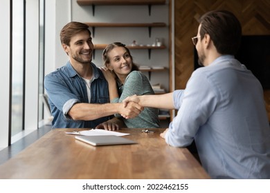 Happy Excited Couple Of Clients And Lawyer Giving Handshakes. Married Customers And Real Estate Broker, Agent, Consultant, House Seller Shaking Hands In Office, Celebrating Property Buying